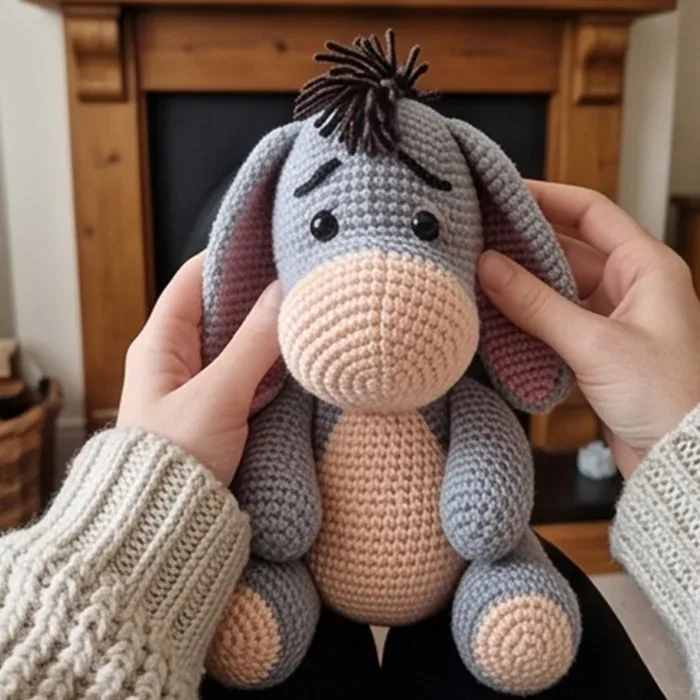 Finished amigurumi held in two hands by the fireplace