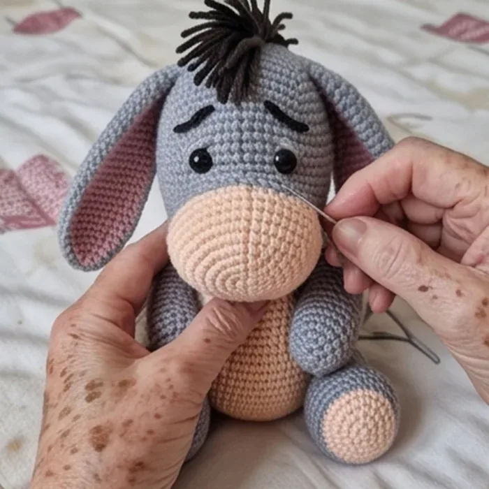 Crocheter sewing the muzzle of the donkey amigurumi